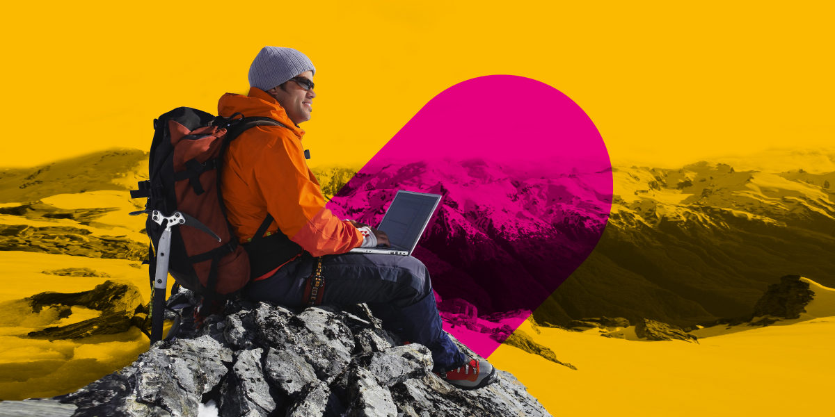 man working on a laptop at the top of a mountain
