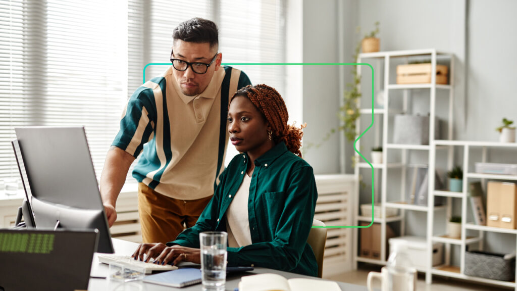 A male and female learner working for a non profit use a LMS system developed by Synergy Learning at a desktop.