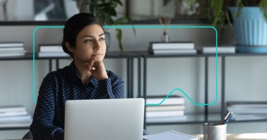 professional woman sits at desktop device using a Learning Management System developed by Synergy Learning.