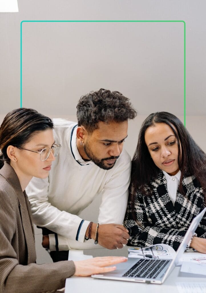 a group of people looking at a laptop with a learning management system displaying compliance training - synergy learning