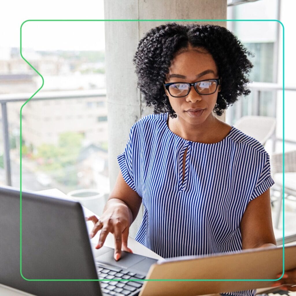 A woman looking at her laptop and using compliance reporting features on her learning management system - Synergy Learning